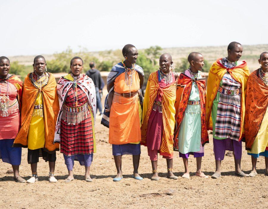 A group of Maasai people in traditional attire celebrating in the Kenyan plains.
